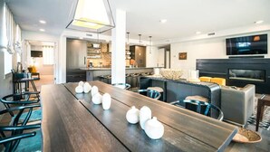A modern living room with a long wooden table, a fireplace, and a television mounted on the wall. - Sleek Park City Main St Rental: Steps to Ski Lift (Park City)