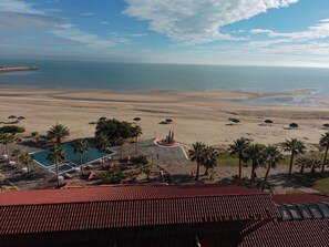 Un complexe hôtelier de bord de mer doté d’une piscine, de palmiers et offrant une vue sur l’océan.