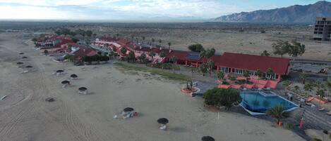A resort with a pool, beach chairs, and a red-roofed building.