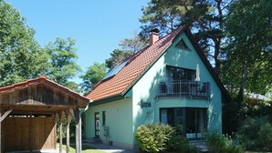 A two-story house with a green facade and a red-tiled roof. - Quiet 55 m² apartment, 3 pers., parking lot, bicycle shed, stove, WLAN (Prerow)
