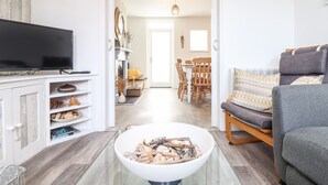 Una sala de estar con televisor, un cuenco de madera, un sofá y un comedor con sillas y una mesa.