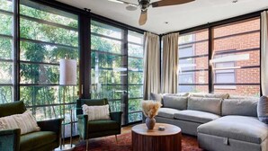 Un soggiorno moderno con ampie finestre, una ventola a soffitto e un divano componibile.