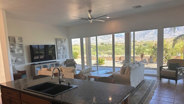 A modern kitchen with a granite countertop, built-in dishwasher, and a dining area with a table and chairs. - Resort Golf Course Living With Amazing Golf and Mountain Views (Tucson)