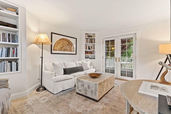 Living room with smart TV, couch, accent chairs and entrance to private deck/garden.