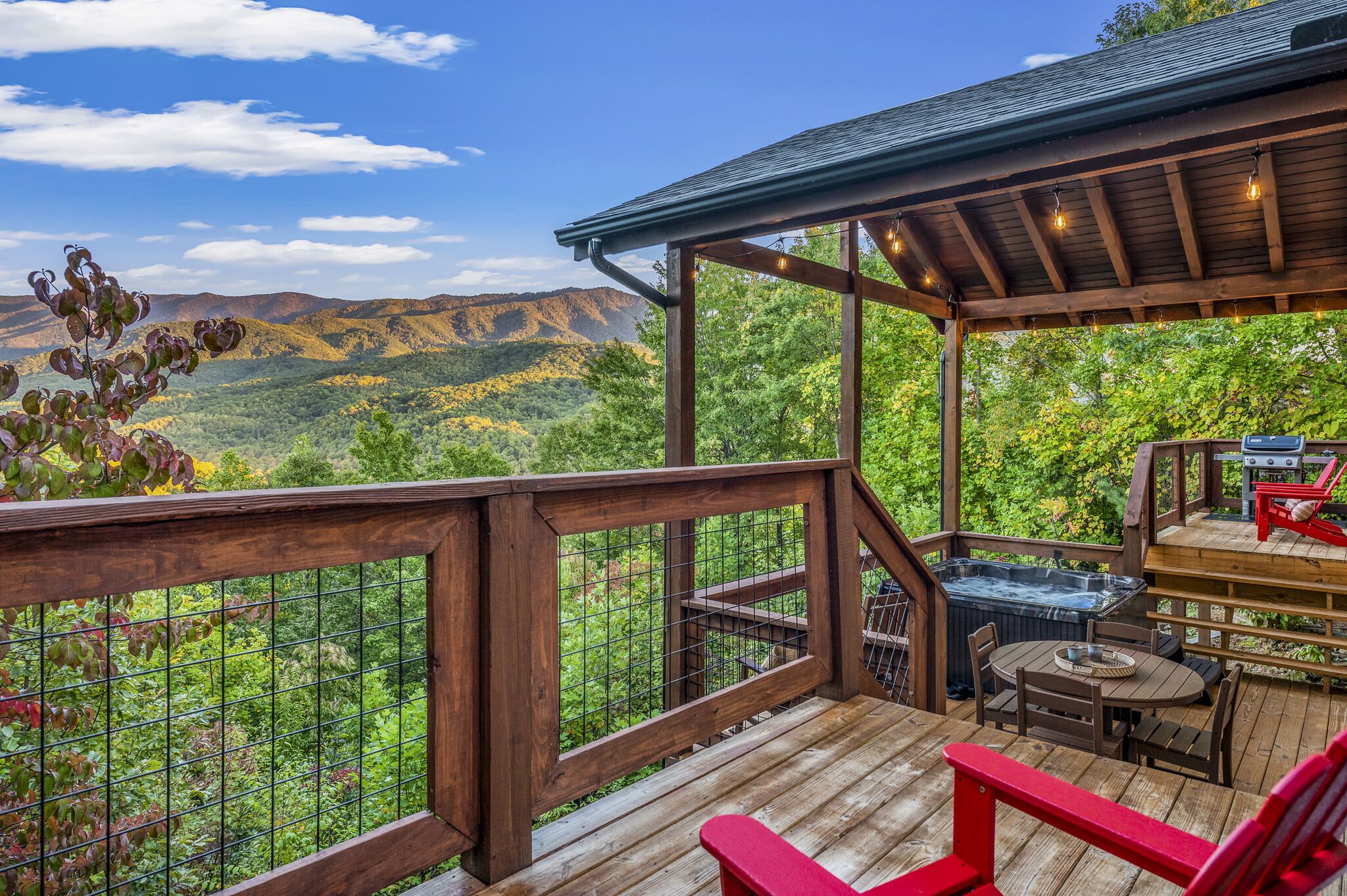Une terrasse en bois avec un jacuzzi, des sièges et une vue sur un paysage montagneux.