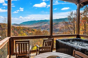 A wooden deck with a hot tub and chairs overlooking a mountainous landscape with autumn foliage. - THE Smoky Mountain Views, Comfort, Style, Games  (Gatlinburg)