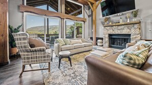 A spacious living room with a stone fireplace, large windows, and a cozy seating area. - THE Smoky Mountain Views, Comfort, Style, Games  (Gatlinburg)