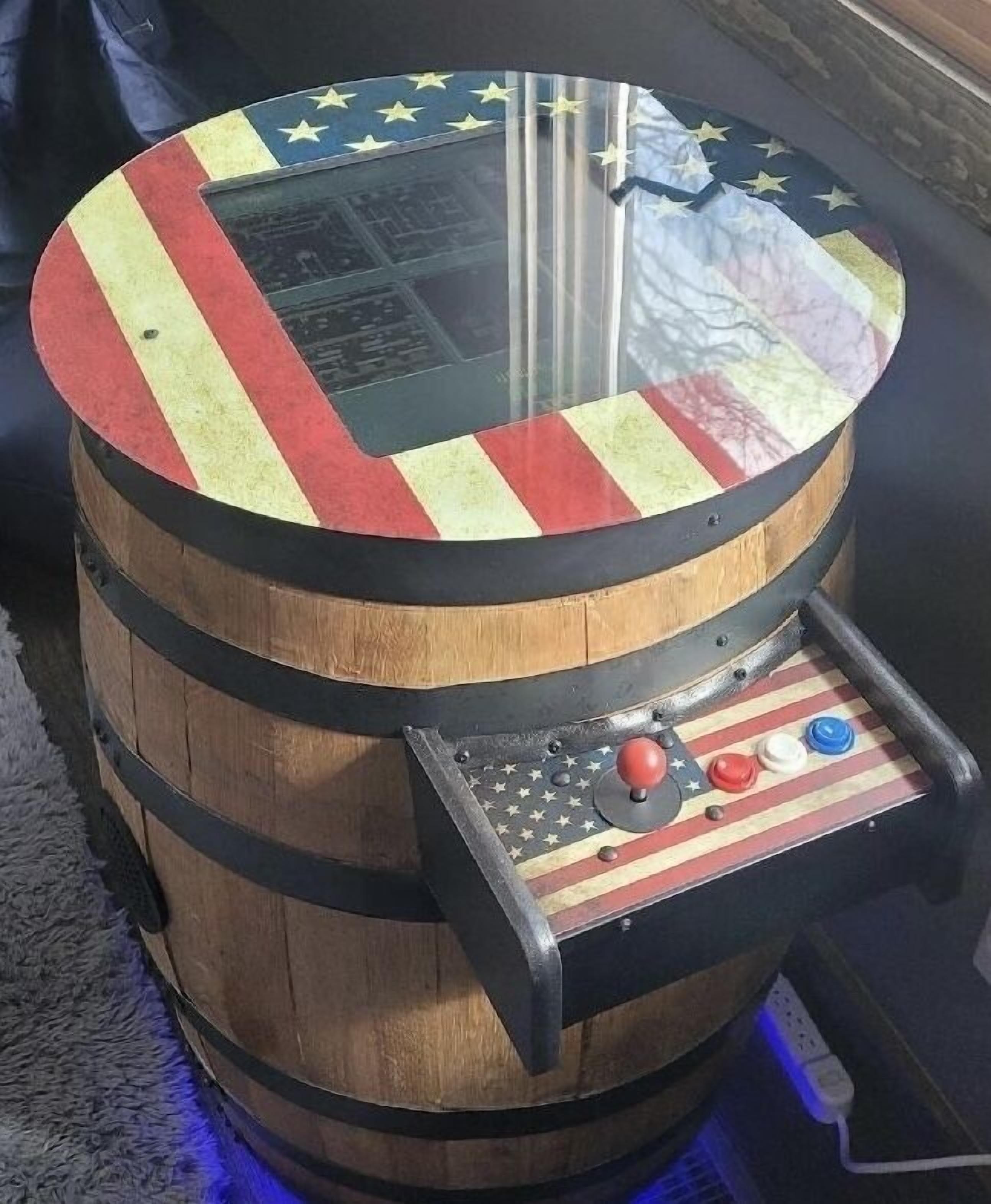 Un barril de madera con un panel de control que incluye botones y un joystick, probablemente parte de una máquina de videojuegos.