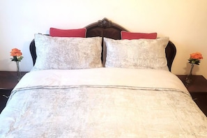 Restful retreat with a plush bed, adorned with a duvet and two pillows, and complemented by elegant vases with flowers.