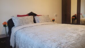 Un lit bien fait, avec une couvre-lit à motifs, deux oreillers et un vase rempli de fleurs posé sur une table de chevet.