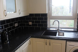 Enjoy cooking in this well-equipped kitchen with a dishwasher and window overlooking lush greenery.