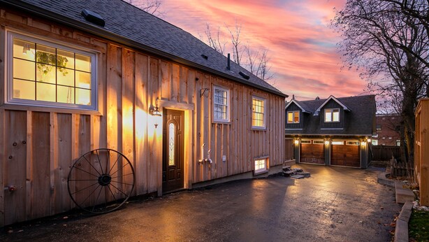 Una casa de madera con garaje, una rueda grande y un camino de entrada.