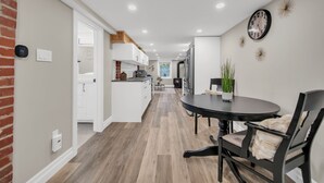 Una cocina moderna con armarios blancos, una isla central y un comedor con una mesa redonda y sillas.