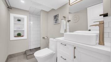 Une salle de bain moderne équipée de toilettes, d’un lavabo et d’un espace douche.