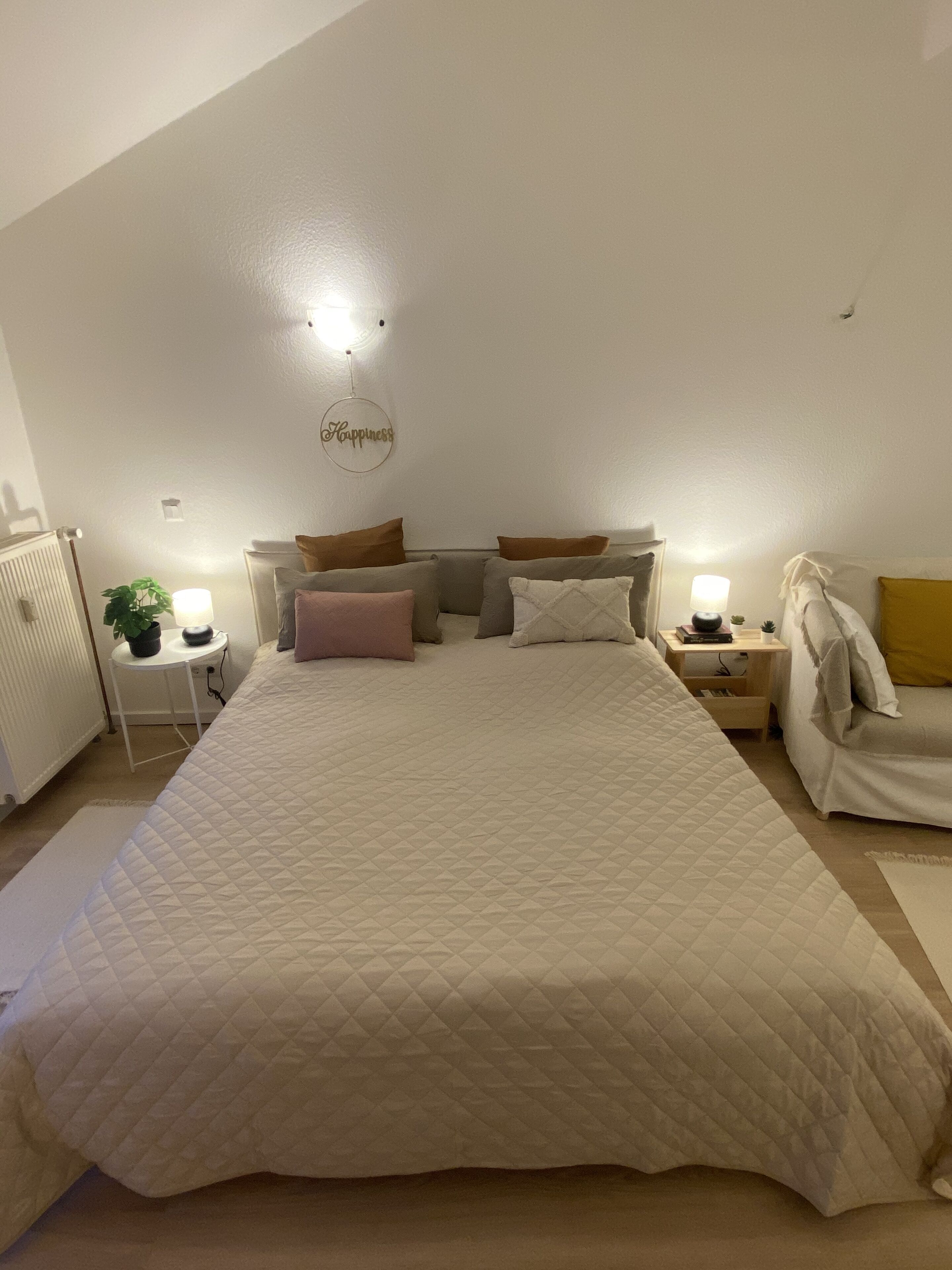 Ein Schlafzimmer mit einem großen Bett, zwei Nachttischen, einer Wandleuchte und einer Deckenleuchte.