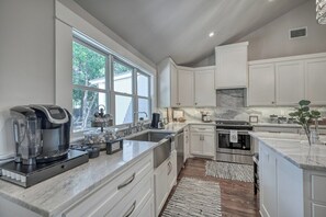 A modern kitchen with white cabinetry, a built-in oven, and a coffee maker on the counter.