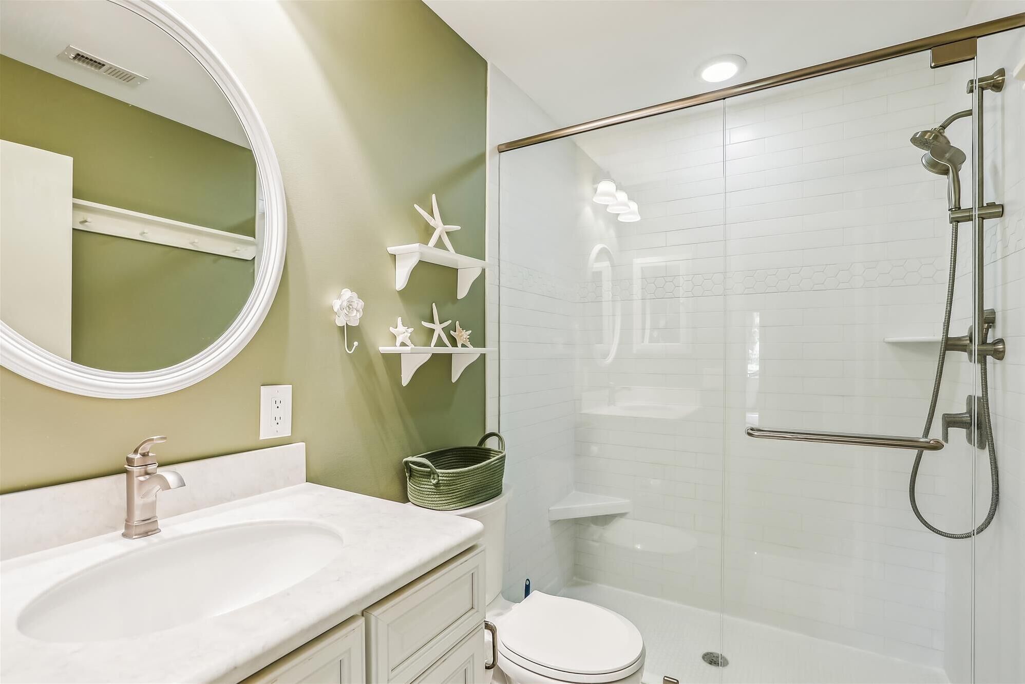 A bathroom with a white sink, a toilet, and a glass-enclosed shower.