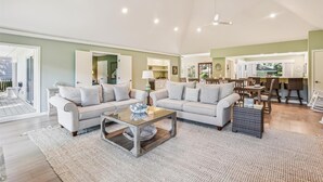 Ein geräumiges Wohnzimmer mit einer großen Sofagarnitur, einem Couchtisch und einem Essbereich mit Holzsesseln und einem Tisch.