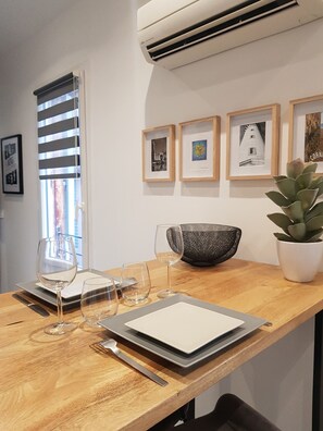 A dining area with a wooden table, framed artwork, and a potted plant. - Atypique 8 (Sète)