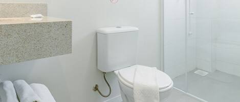 Un baño moderno con inodoro, lavamanos y ducha.