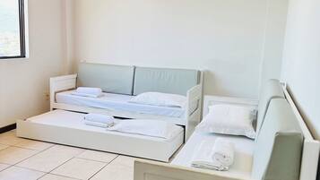 A hotel room with two beds, a desk with a phone and remote controls, and a ceiling fan.