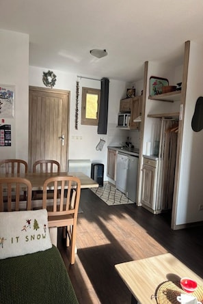 Una cocina compacta con armarios de madera, un microondas y un lavamanos.