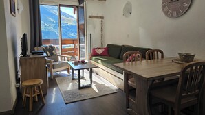 Un accogliente soggiorno con un tavolo da pranzo in legno, sedie, un divano e un grande orologio a parete.