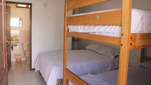 A room with two bunk beds, a sink, and a toilet in the background. - Hotel Manhattan Salinas Ecuador (Salinas)