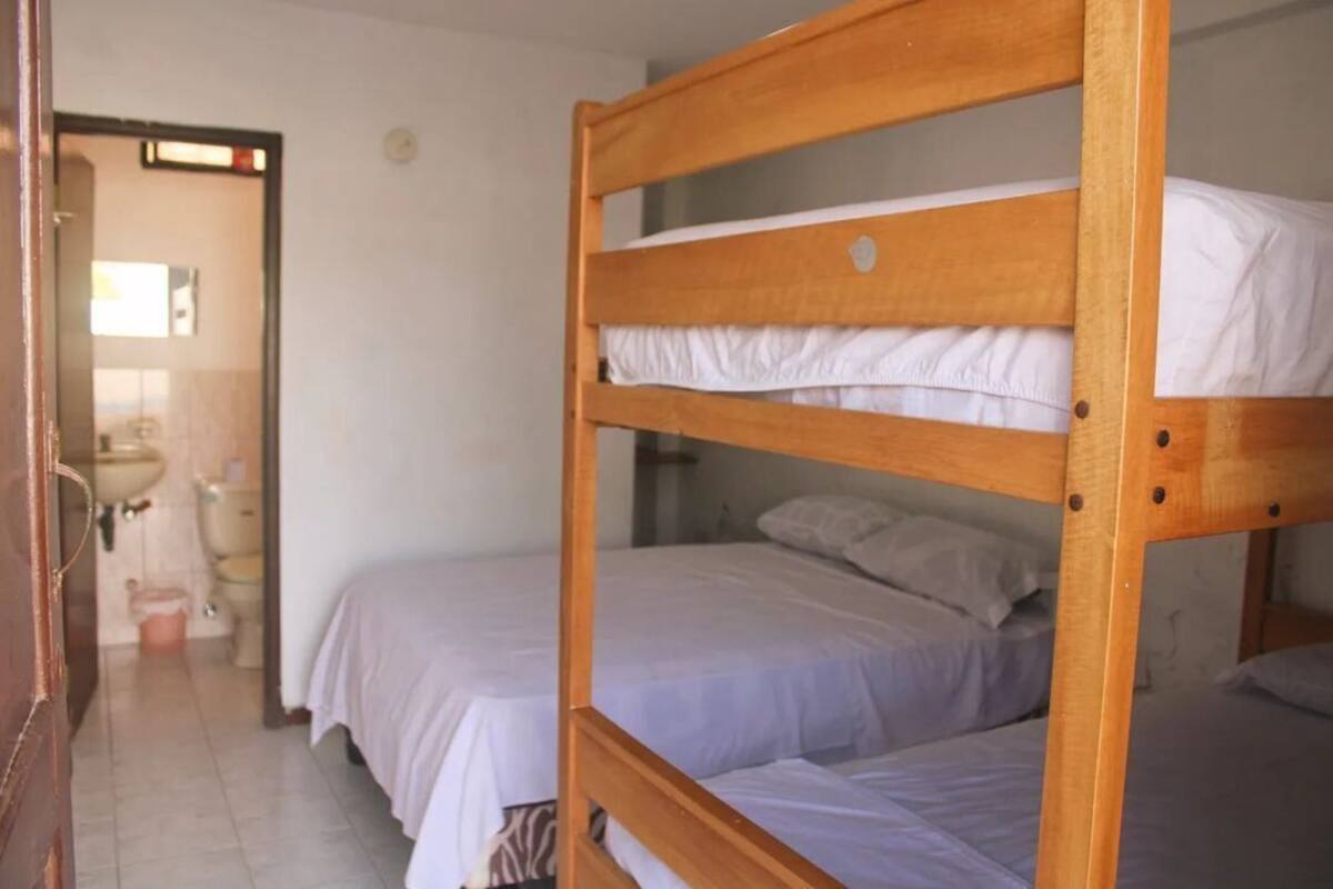 Una habitación con dos literas, un lavabo y un inodoro al fondo.