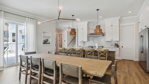 Una cocina moderna con una isla grande, armarios blancos e iluminación colgante.