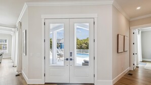 Un vestíbulo amplio con un par de puertas que dan a un balcón con vista a la piscina.