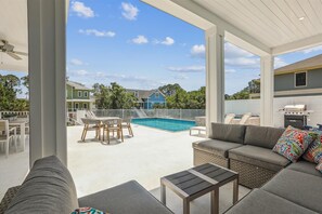 Eine Außenpatio mit Pool, Grill und Sitzgruppe mit Sofa und Tisch.