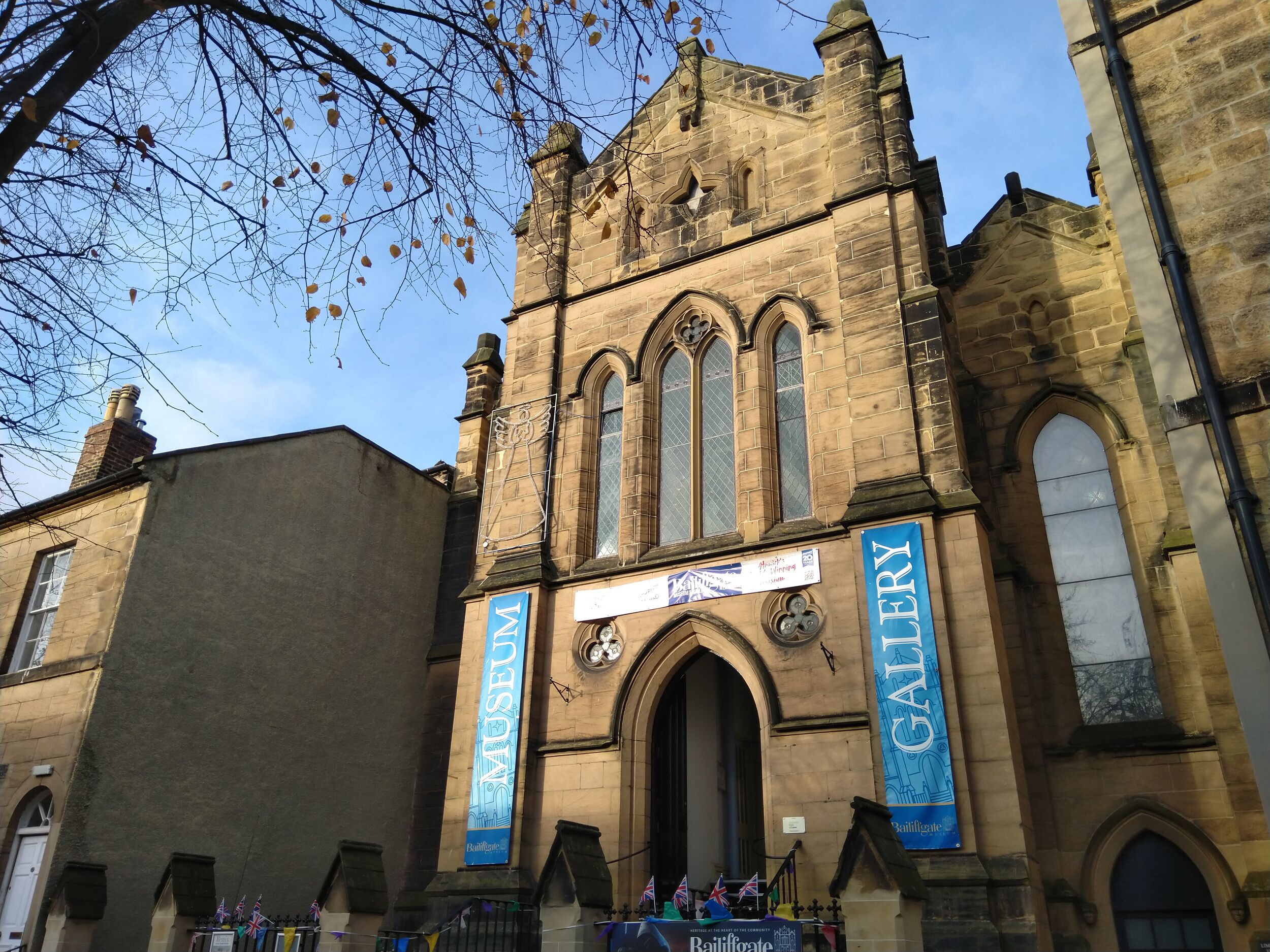 A historic building with large arched windows and banners for the Museum and Gallery.