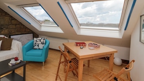 Ein Loft-Zimmer mit Holzboden, einem blauen Sofa, einem Holztisch und zwei Dachfenstern.