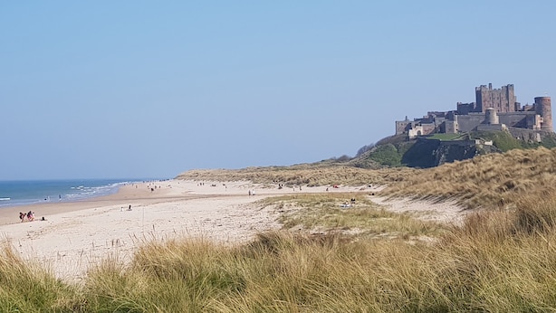 Ein Strand mit einer Burg auf einem Hügel.
