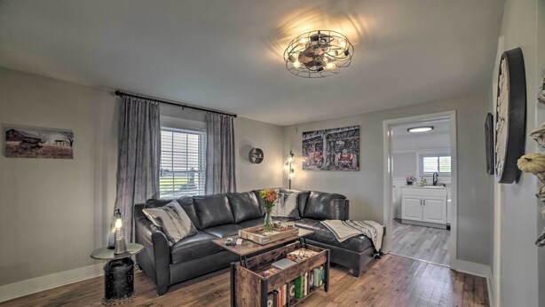 A modern living room with a sectional sofa, a coffee table with books, a floor lamp, and a chandelier.