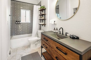 A bathroom with a bathtub, toilet, vanity with a sink, and a mirror. - Denver with Hot Tub, Corn Hole, Ping Pong & Grill (Arvada)