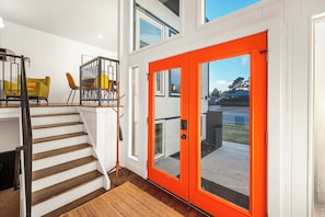 A staircase leading to a bright room with a red door, a yellow chair, and a dining table. - Denver with Hot Tub, Corn Hole, Ping Pong & Grill (Arvada)