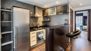 A modern kitchen with a built-in refrigerator, stove, oven, and bar stool. - Kifkif One (Bejaad)