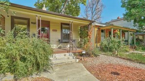 A two-story house with a porch, a front door, and a small staircase leading to the entrance. - Game Parlour! Downtown Workspace BBQ Fire Pit (Colorado Springs)