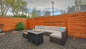 A backyard with a wooden fence, a fire pit, a sectional sofa, and a small shed. - Game Parlour! Downtown Workspace BBQ Fire Pit (Colorado Springs)
