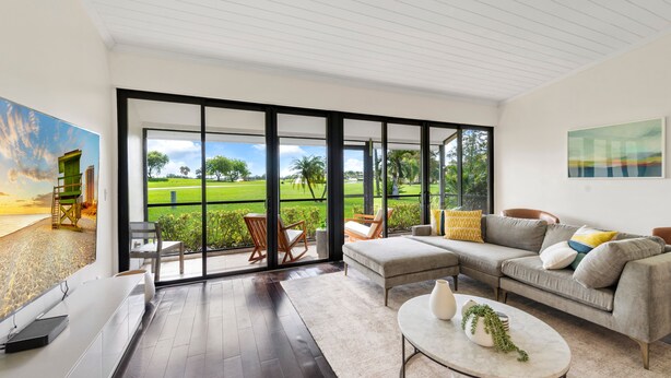 A modern living room with a large sliding glass door leading to a green outdoor area.
