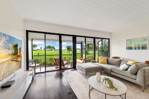 A modern living room with a large sliding glass door leading to a green outdoor area. - New PGA Home on Fazio Golf Course w/ Amazing 180º Views by Guaranteed Rental™ (Palm Beach Gardens)