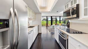 A modern kitchen with stainless steel appliances, a large window, and a view of the outdoors.