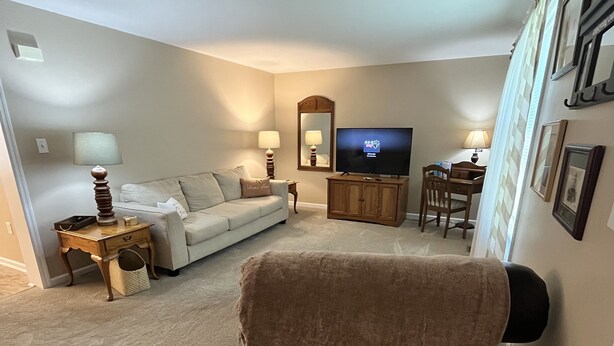 Ein Wohnzimmer mit Sofa, Fernseher, Couchtisch und Essbereich.