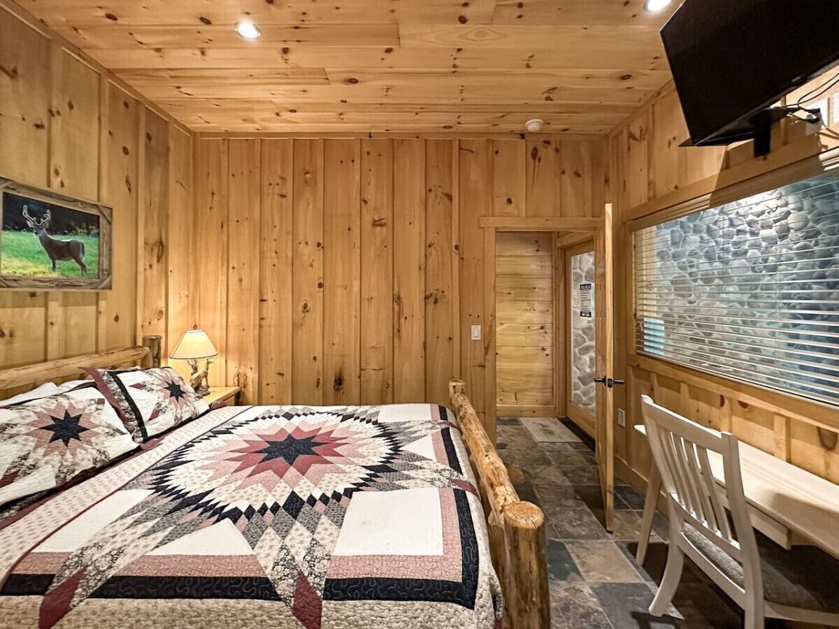 Een houten kamer met een bed, een bureau en een televisie.