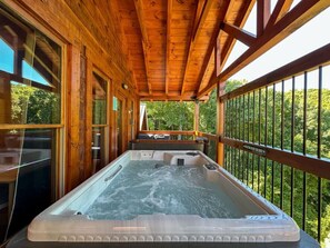 A wooden deck with a hot tub, wooden railings, and a view of trees. - Gatlinburg Cabin w/ Indoor Heated Pool & Hot Tub (Gatlinburg)