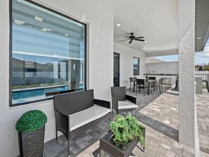 Relax on the patio with a sofa, chairs, and table, offering a view of the pool and surrounding buildings.