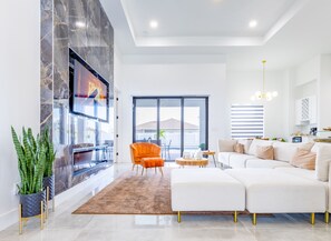 Relax in this stylish living room with a large flat-screen TV, comfortable seating, and a balcony with a view.
