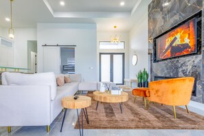 Relax in this stylish living room with a sofa, coffee table, and armchair, featuring a flat-screen TV and large window.